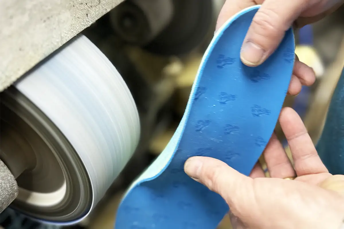 Technician handcrafting and shaping a custom orthotic insole using specialist grinding equipment at Dr Insole.